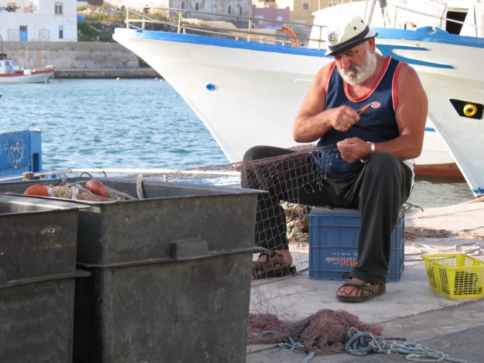 Pescatore artigianale mentre ripara le reti nel porto di Lampedusa. I pescatori con molti anni di esperienza sono osservatori attenti e testimoni preziosi dei cambiamenti ecologici in atto. Foto: Pierpaolo Giordano - ISPRA